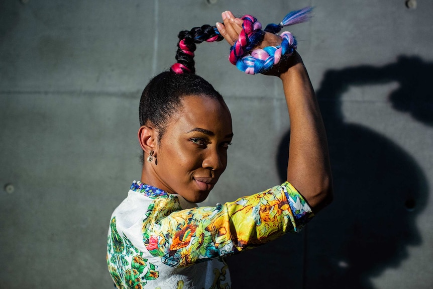 Portrait of Kalypso Finbar, holding her pink-and-blue hair around her hand, at Carriageworks in February 2019.