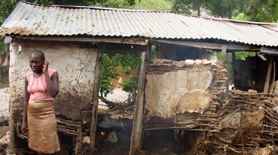 A Haitian woman stands in front of her damaged home east of Port au Prince.