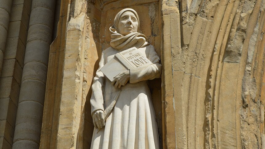 A statue of Julian of Norwich at the exterior of a cathedral