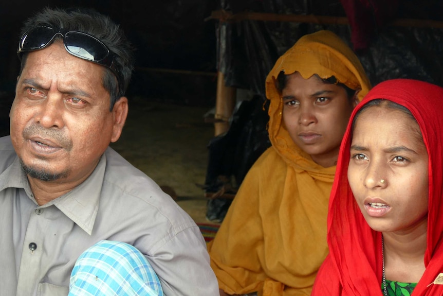 A man and two children sit on the ground