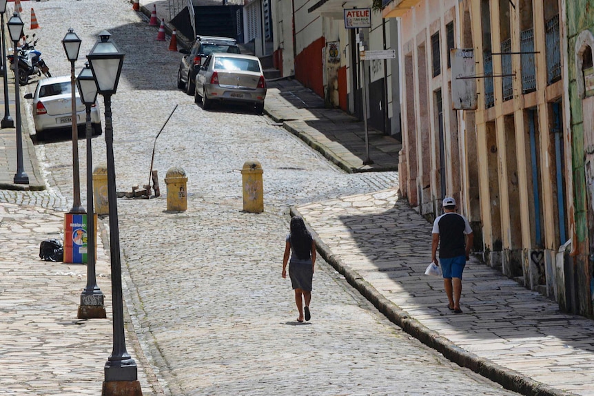 People walking along an empty street in Brazil.