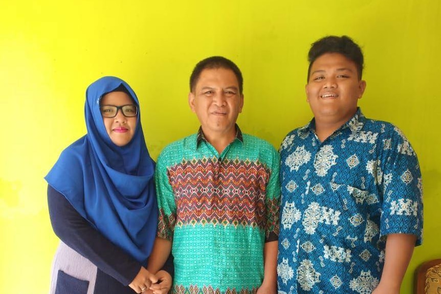 Haringga 'Ari' Sirla stands next to his father and mother.