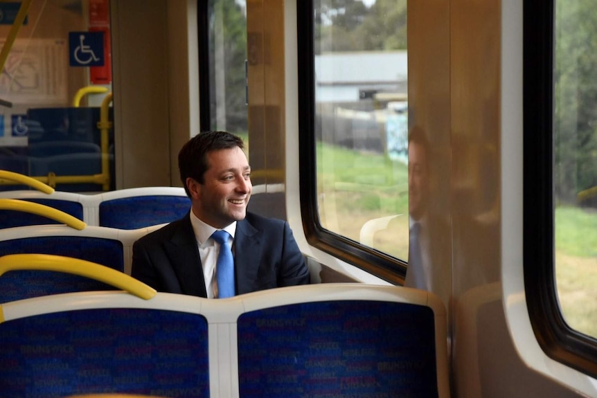Matthew Guy sits on a Melbourne train and smiles as he looks out the window.