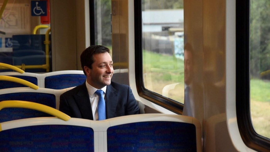 Matthew Guy sits on a Melbourne train and smiles as he looks out the window.