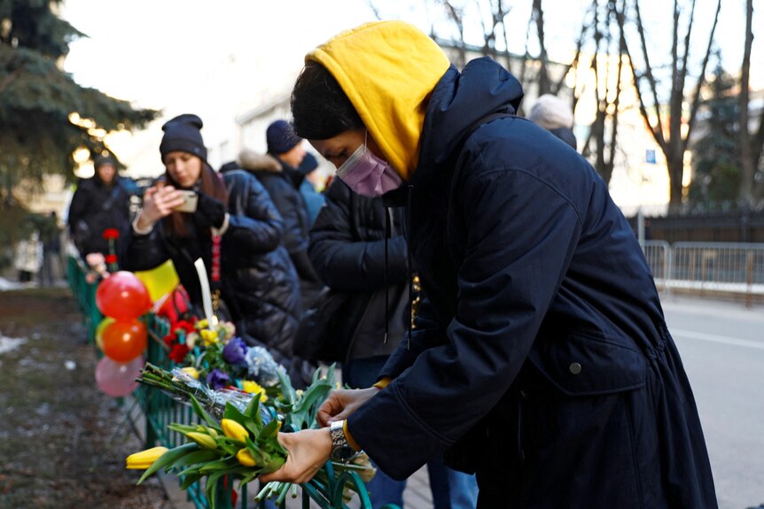 A woman places flowers outside the Ukrainian embassy.