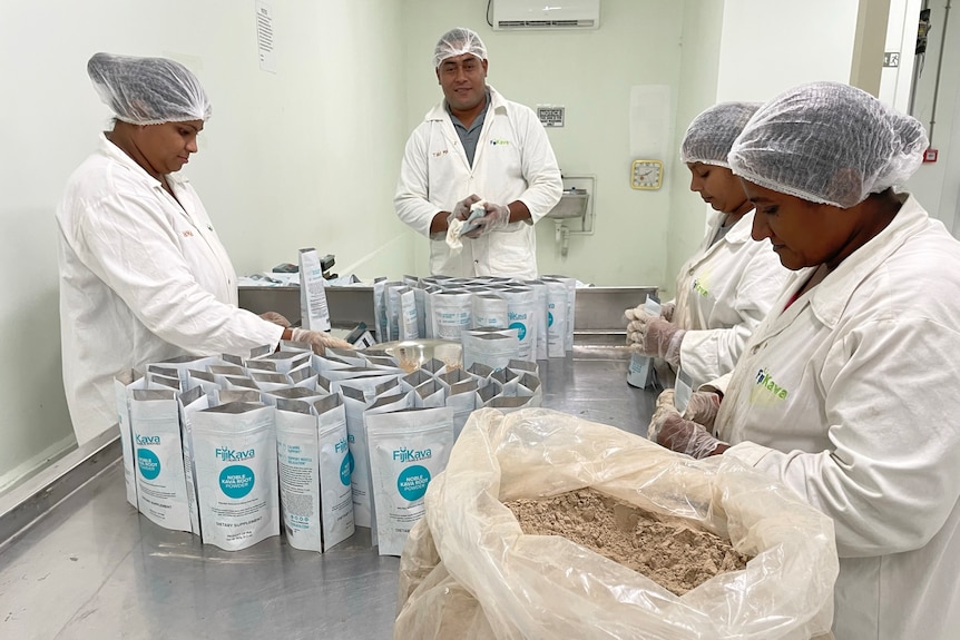 Image of four people in lab coats with a bag of powder and small packets.