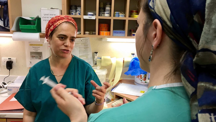 Midwife Daphna Strassberg talks to a colleague behind a nurses' station.