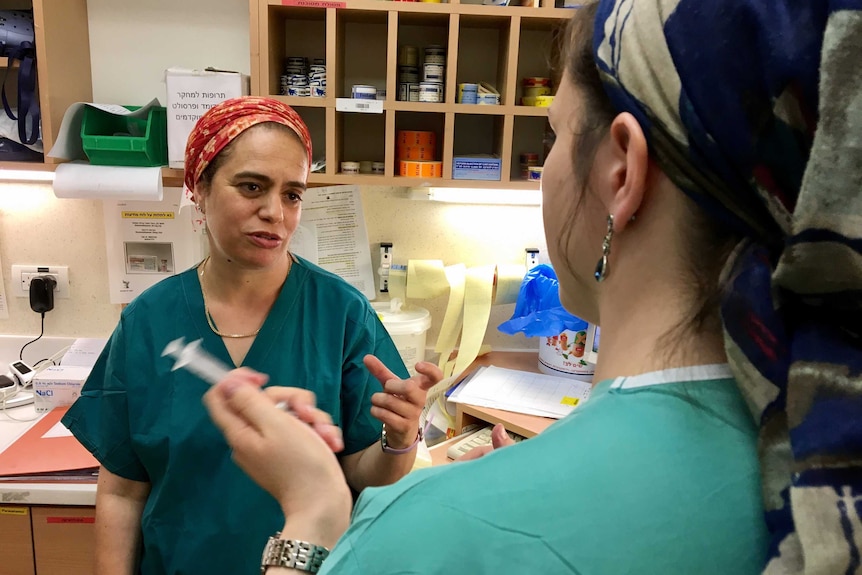 Midwife Daphna Strassberg talks to a colleague behind a nurses' station.