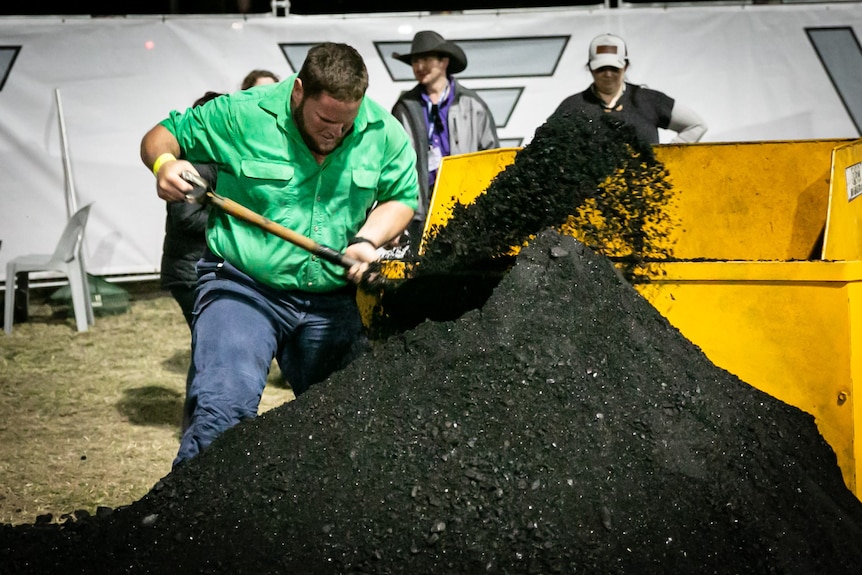 a man wearing a green long sleeve shirt shovelling coal