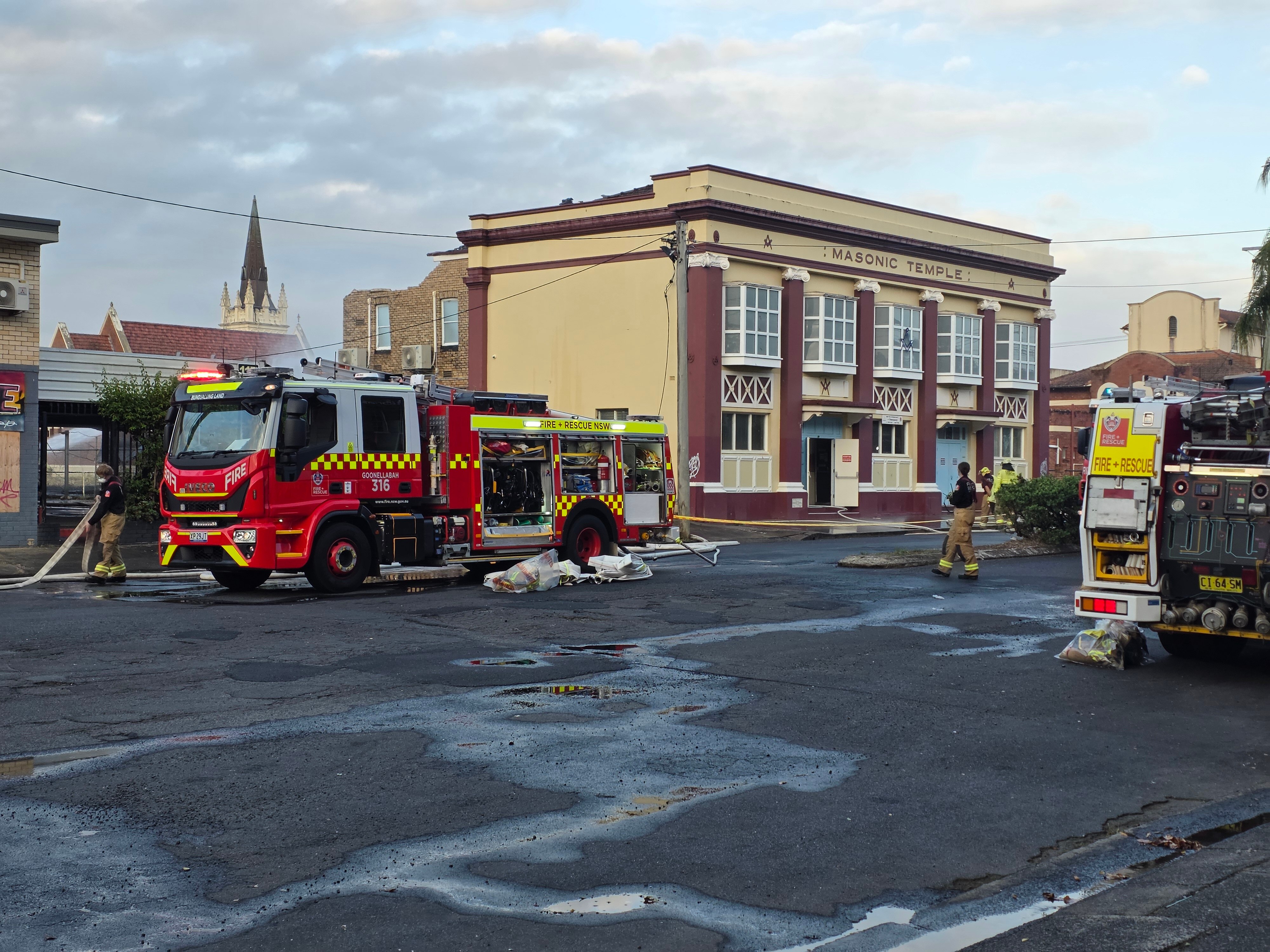 L'extérieur d'un bâtiment orné détruit par un incendie avec un camion de pompiers devant.