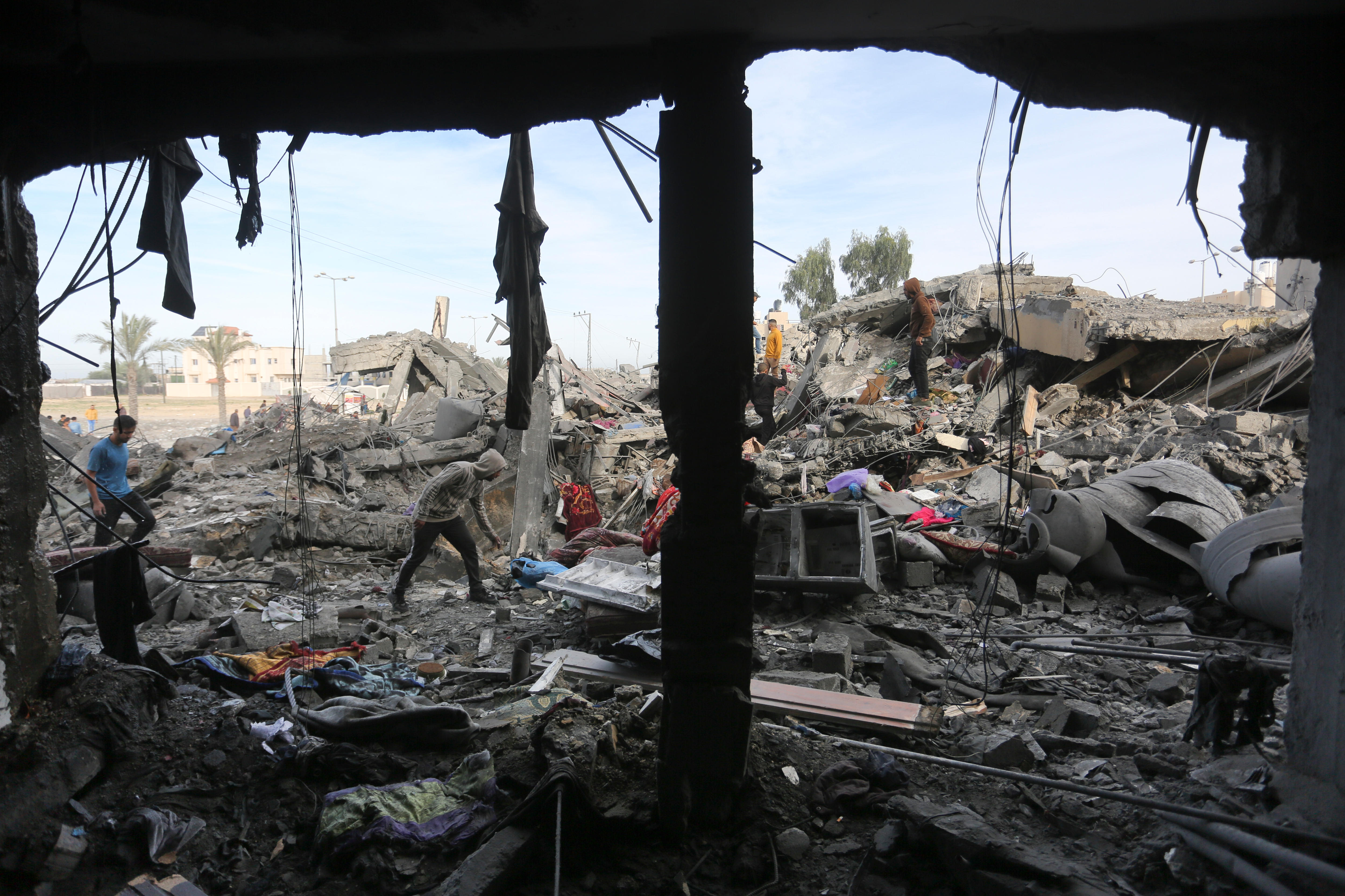 rubble and debris from bombardment while people pick through the rubble