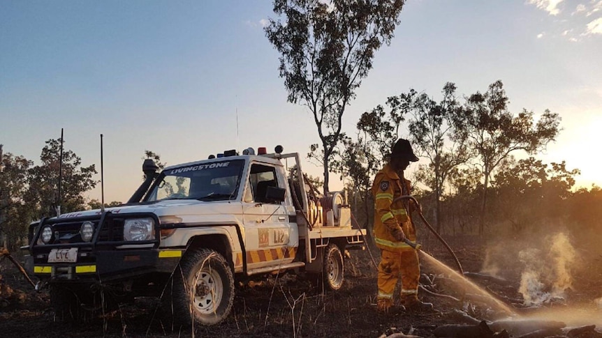 Bush fire NT volunteer with fire unit in background putting out fire.