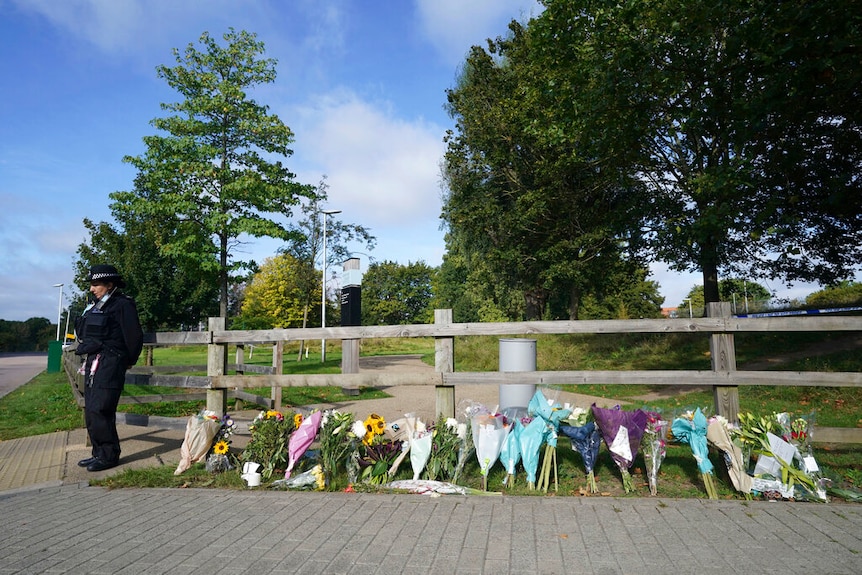 Flower tributes on a fence outside a park.