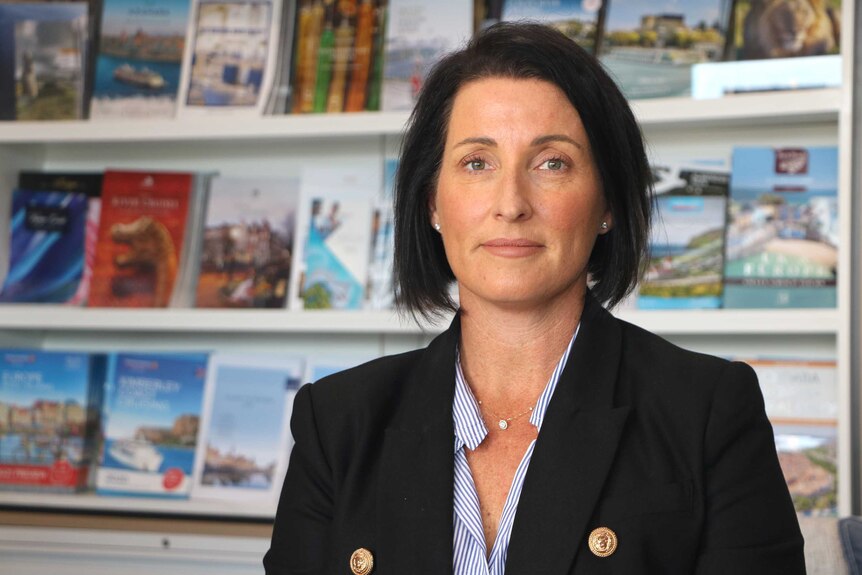 Headshot of a woman with travel brochures in the background.