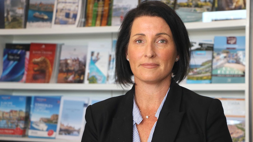 Headshot of a woman with travel brochures in the background.