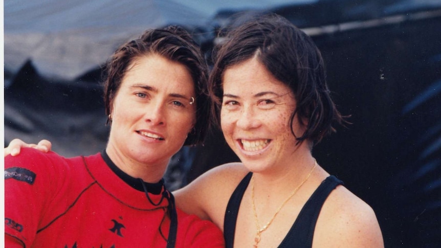 Two young women hugging and smiling to the camera.