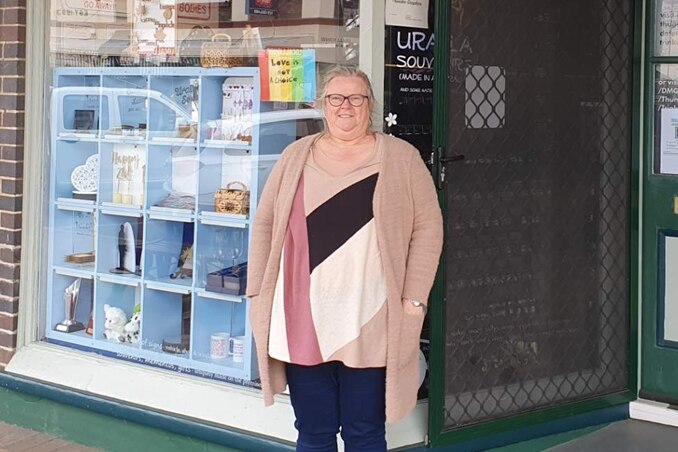 Teresa French standing outside her business in Uralla, 'Thunder Graphics' sign above shopfront window