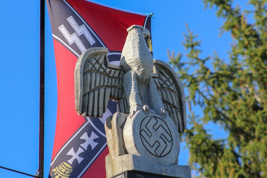 A wood carving of an eagle in front of a Nazi flag