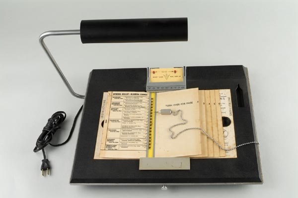 A surface to incorporate punch card ballots and a stylus on a chain used to punch holes in the ballots.