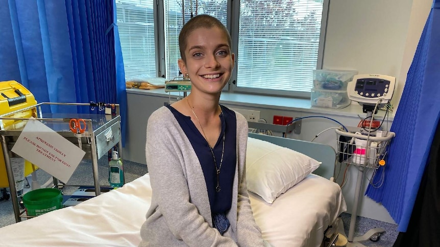 Cancer patient Aliona Grytsenko sits smiling on a hospital bed.
