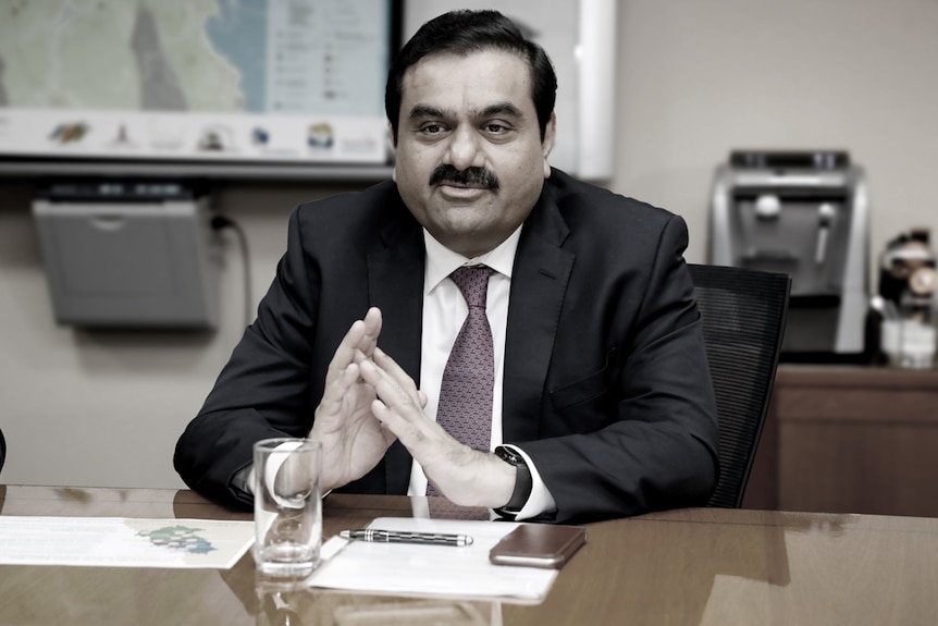 Adani Group chairman Gautam Adani sits at a desk.