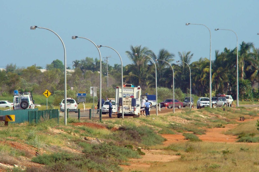 A wide shot of a sunny street filled with police cars