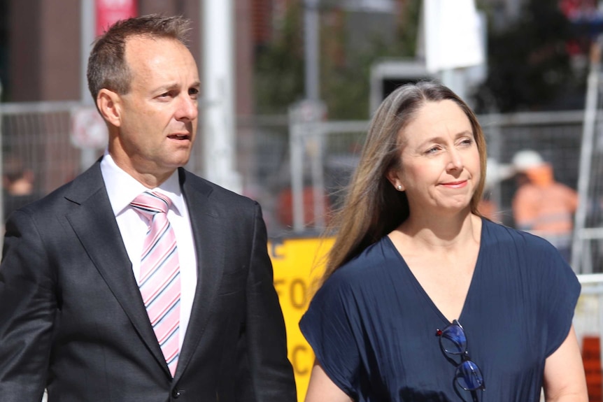 A man and woman walk across roadworks to enter a court building