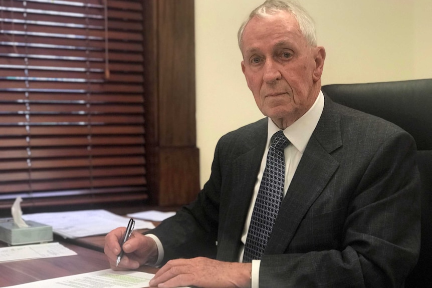 John Darley sits at his desk.