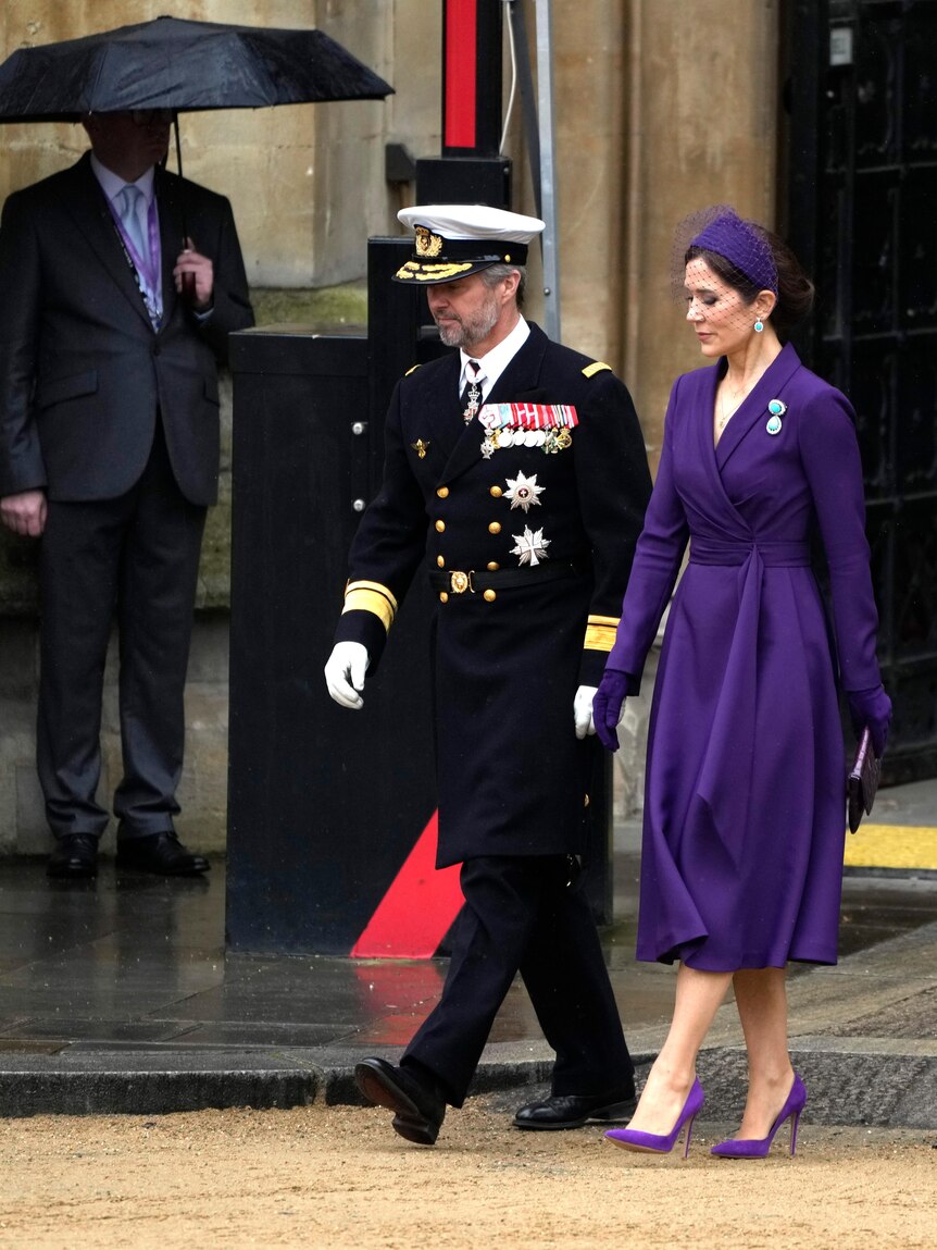 A woman walking alongside a man in uniform