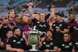 New Zealand All Blacks players celebrate with the Bledisloe Cup after beating the Wallabies in Sydney.