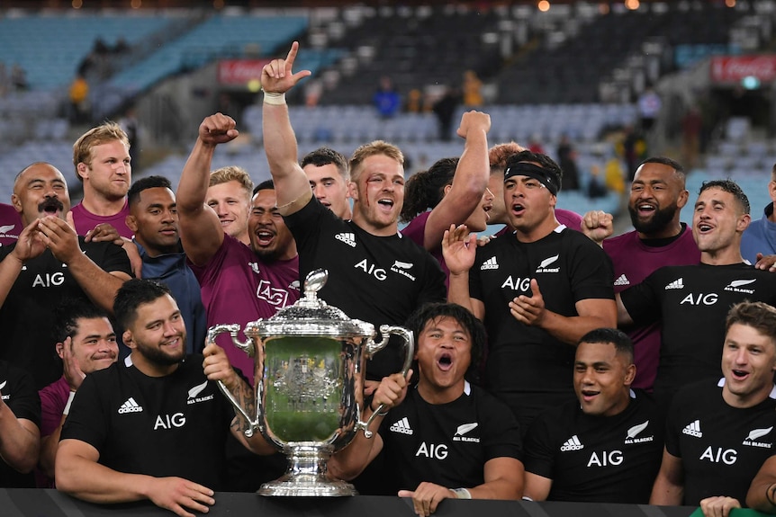 New Zealand All Blacks players celebrate with the Bledisloe Cup after beating the Wallabies in Sydney.