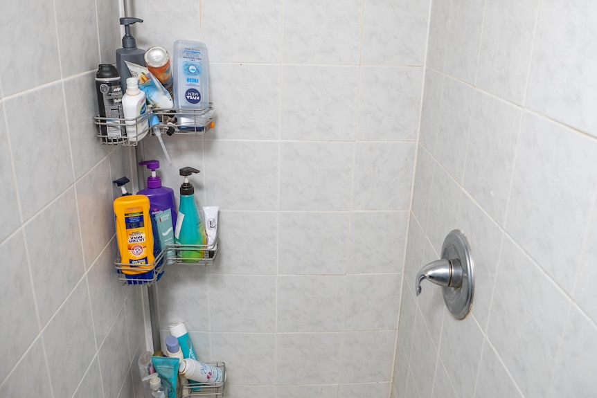 a slightly dirty bathroom packed with shampoo bottles