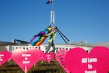 Protester carries rainbow flag in front of Parliament House