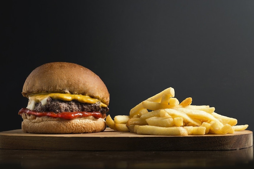 A hamburger and chips on a wooden board.