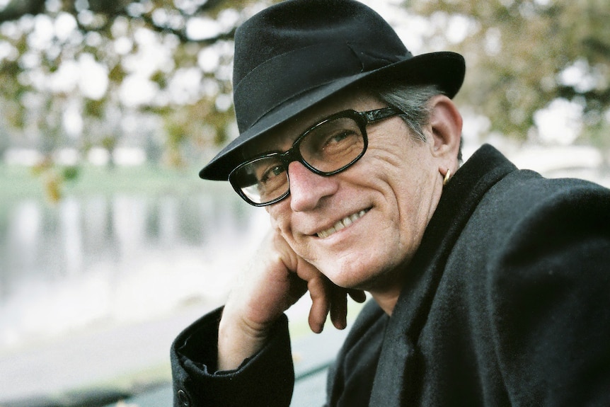 An older man wearing a black hat smiling at the camera