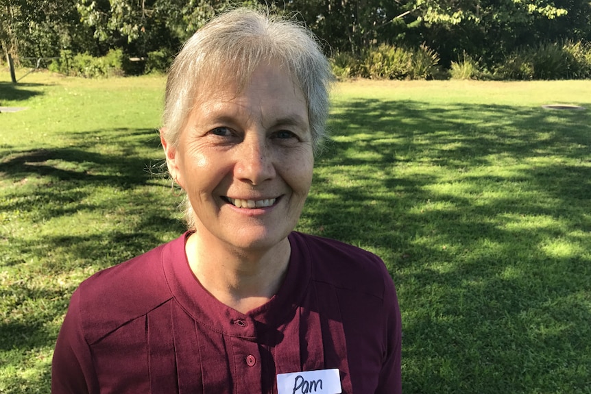 Pam Pittaway smiles at the camera with grass and trees behind her.