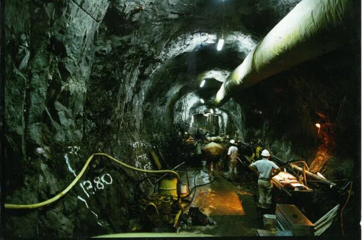 A large tunnel underground with hard-hatted workers in it.