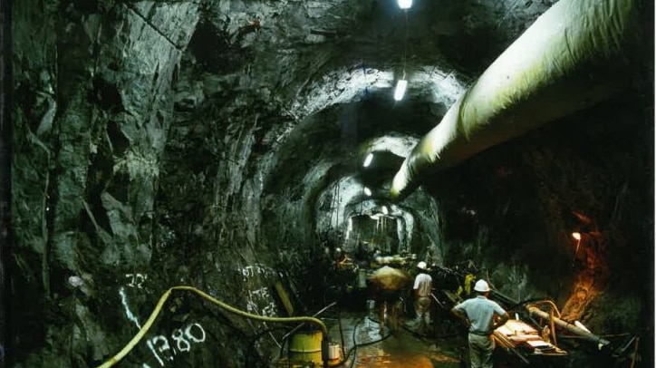 A large tunnel underground with hard-hatted workers in it.