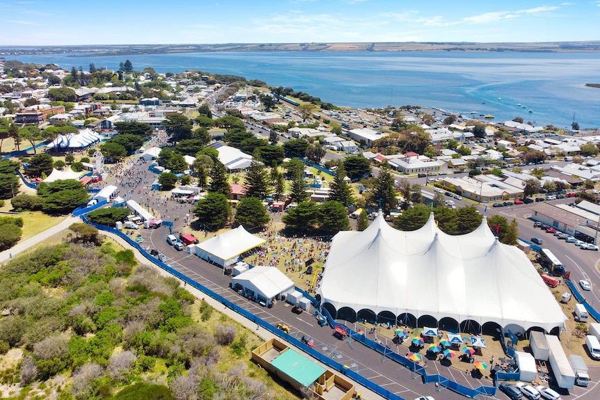 an aerial photo of a music festival in a coastal beach town