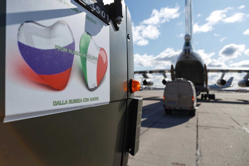 A military plane next to a cargo load with a sign reading "From Russia with Love"