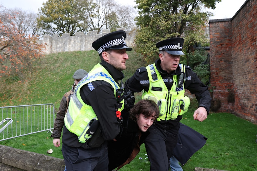 Un hombre está detenido por dos policías. 