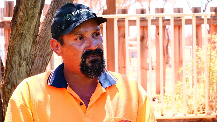 Man in orange shirt with black cap