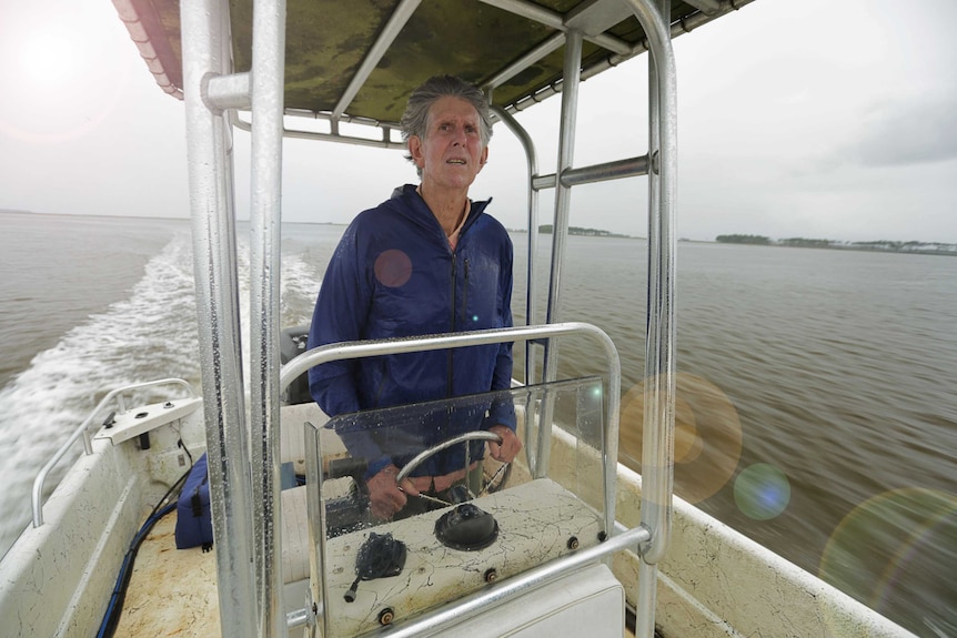 A man standing at the wheel of a boat