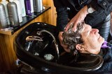 A close-up shot of a hairdresser's hands washing a client's hair.