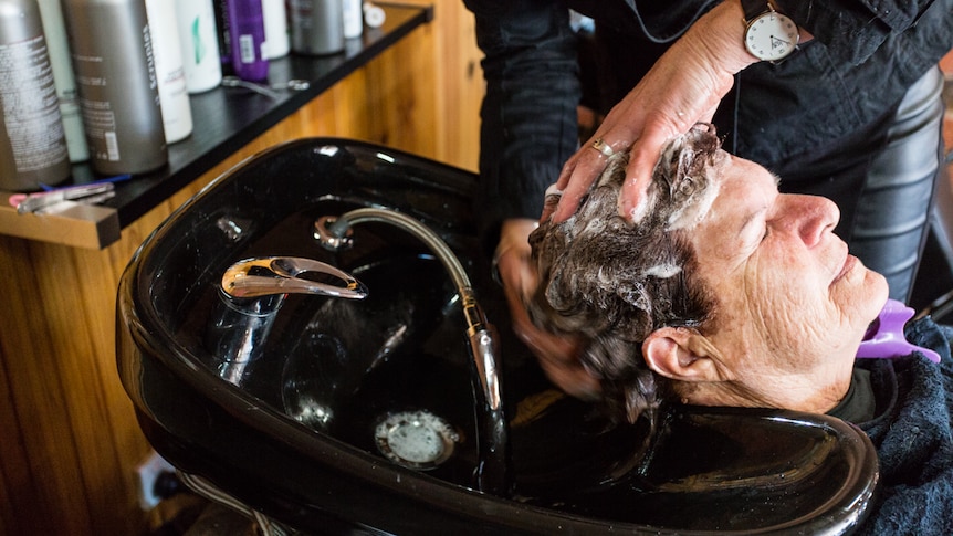 A close-up shot of a hairdresser's hands washing a client's hair.