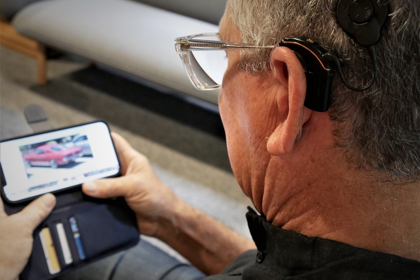 man looking at phone with cochlear implant