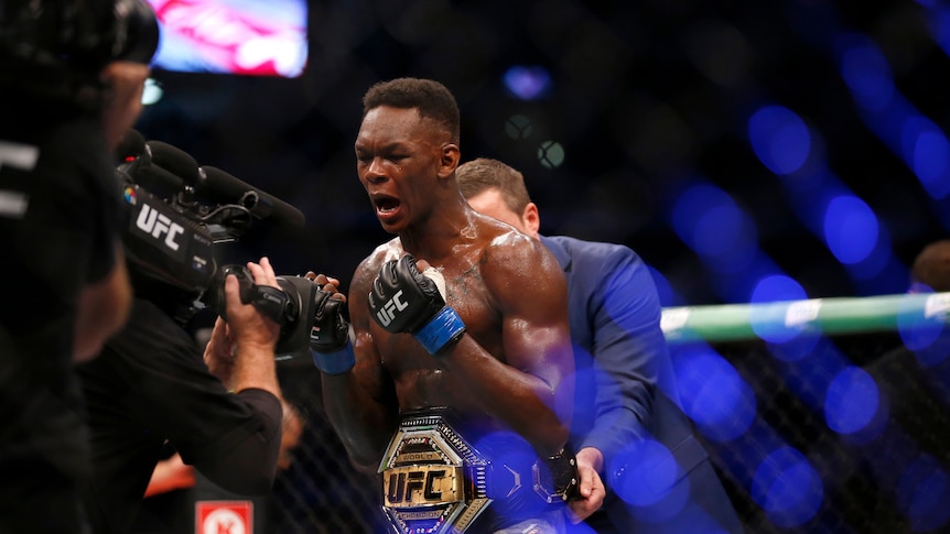 Israel Adesanya celebrates winning the title 