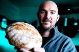 Home baker Scott Mitchell holding a loaf of sourdough bread from his recipe.