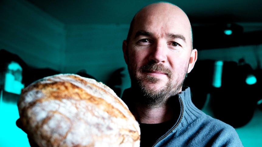 Home baker Scott Mitchell holding a loaf of sourdough bread from his recipe.