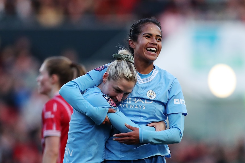 Manchester City teammates Mary Fowler and Laura Coombs hug after a goal during a Women's Super League game.